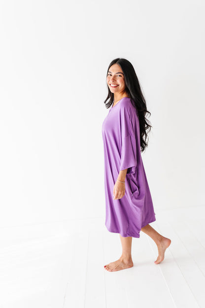 A woman stands barefoot on a white floor, smiling at the camera in the Jammie Session Block Party Solid Women's Muumuu Lounge Tee (ONE SIZE FITS XS - XXL), set against a plain white background.