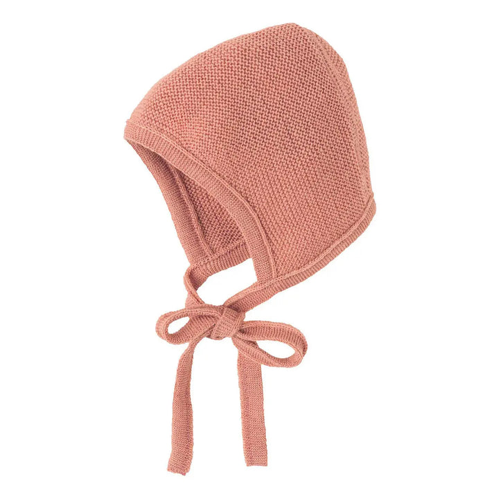Le bonnet en laine mérinos tricotée est parfait pour les premières promenades de bébé dehors. 2 tailles disponibles. Coloris Soft pink.