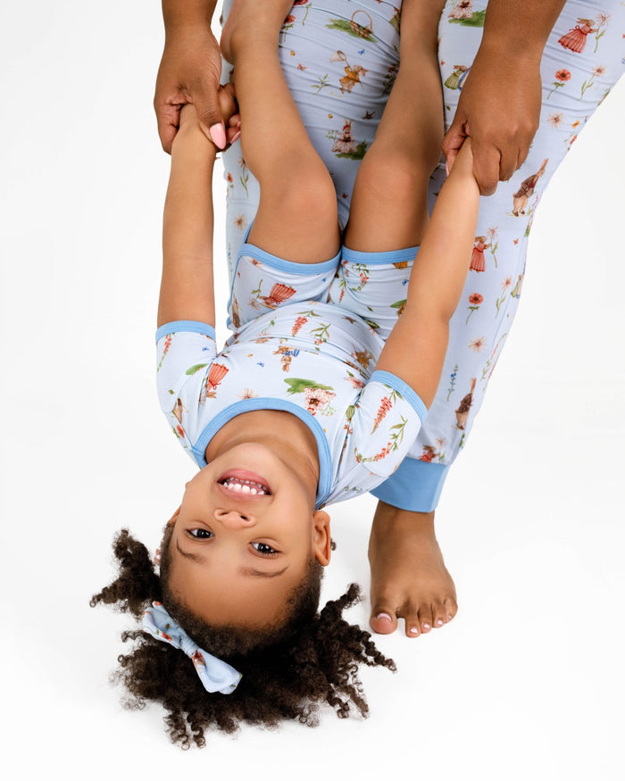 An adult holds a smiling child upside down by the hands. Both wear matching Jammie Session ‚ÄúDon‚Äôt Worry, Be Hoppy (Rabbit)‚Äù short pajama sets, which are hypoallergenic and ideal for sensitive skin.