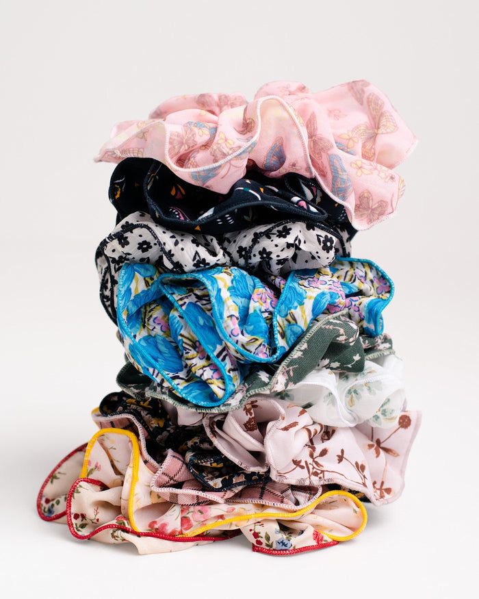 A stack of Jammie Session Handmade Scrunchies, including silk pieces with floral and patterned designs, crafted by work-at-home moms, displayed against a plain white background.