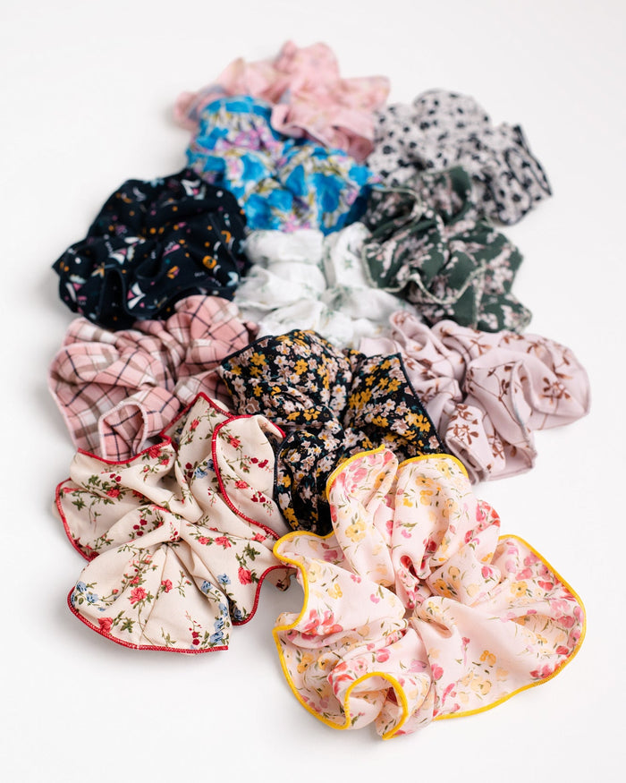 Jammie Session Handmade Scrunchies, featuring various patterned and floral designs crafted by work-at-home moms, are arranged in a semi-circle on a white background.