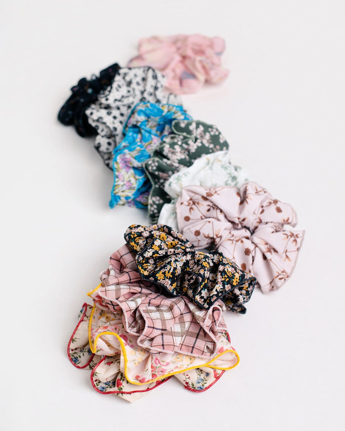 Jammie Session Handmade Scrunchies, including luxurious silk options, are beautifully displayed in a loose curve on a white surface‚Äîperfect handcrafted accessories made by work-at-home moms.