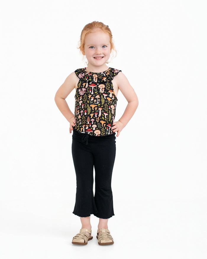A young child with light skin and red hair smiles against a white background, wearing the Jammie Session Mystic Mushrooms Bloomy Crop Set.