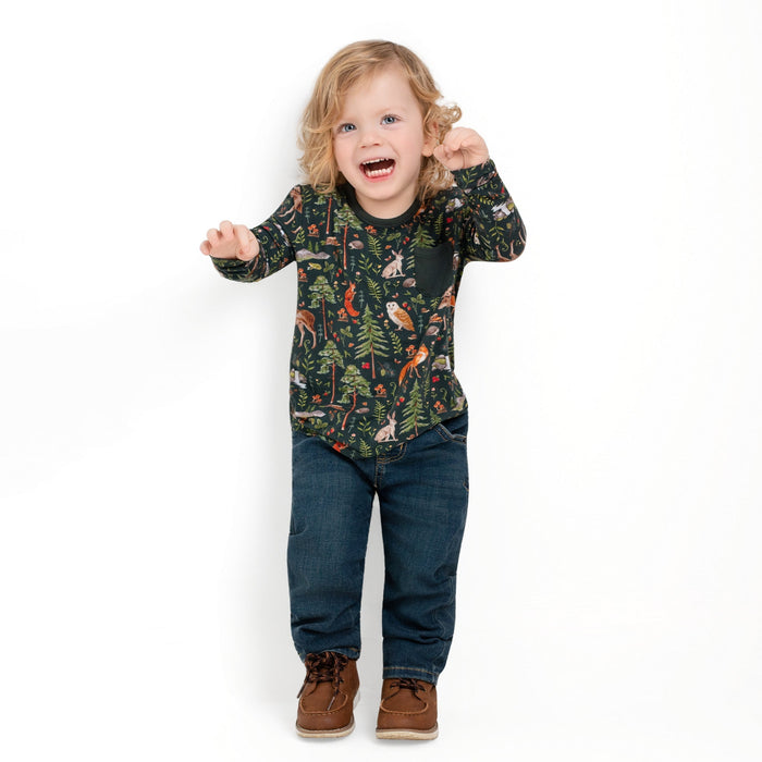 A smiling blond toddler wears the Jammie Session "Wood You Be My Friend" Kids' Long Sleeve T-shirt, featuring a forest animal print‚Äîperfect hypoallergenic clothing for sensitive skin.